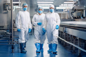 Medewerkers lopen in industriële en foodomgeving en dragen witte disposable werkkleding.