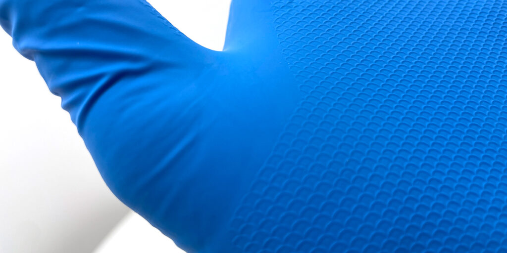 Close-up afbeelding van blauwe handschoen met structuur en deels glad oppervlak