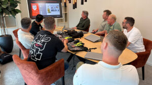 Deelnemers volgen een producttraining door Guide Gloves in een vergaderruimte.