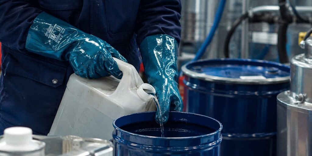 Medewerker gebruikt Guide chemisch bestendige veiligheidshandschoenen tijdens werkzaamheden met chemische vloeistoffen.