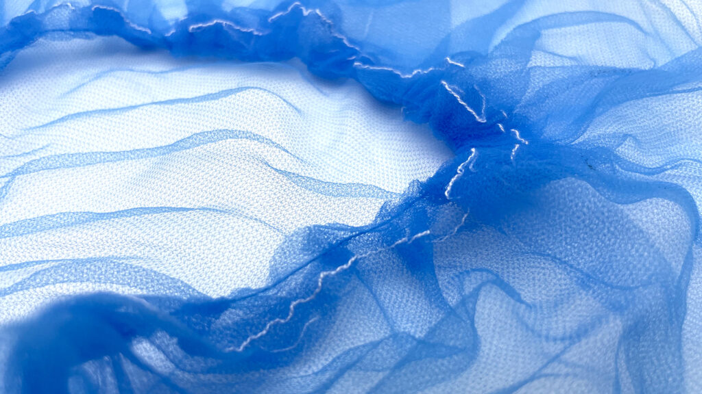 Close-up of a blue disposable hairnet showing the fine mesh structure.