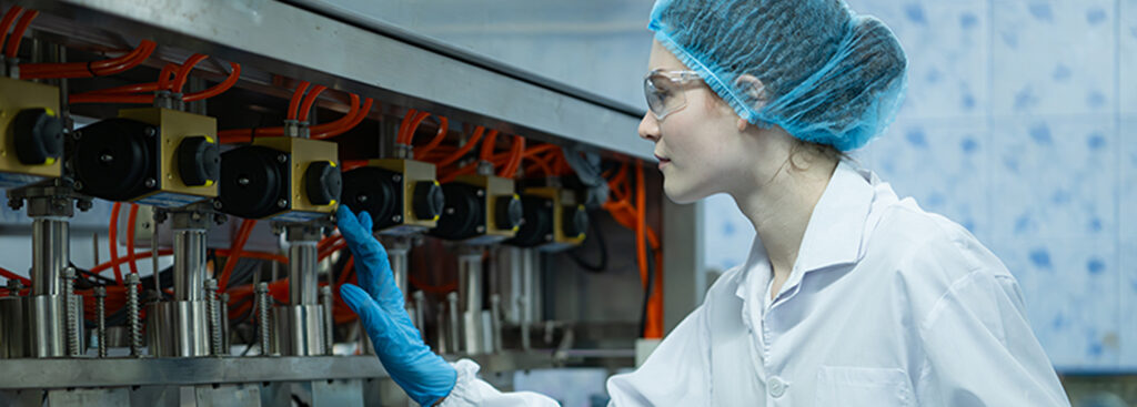 Worker in the food industry wearing PPE while operating a production machine