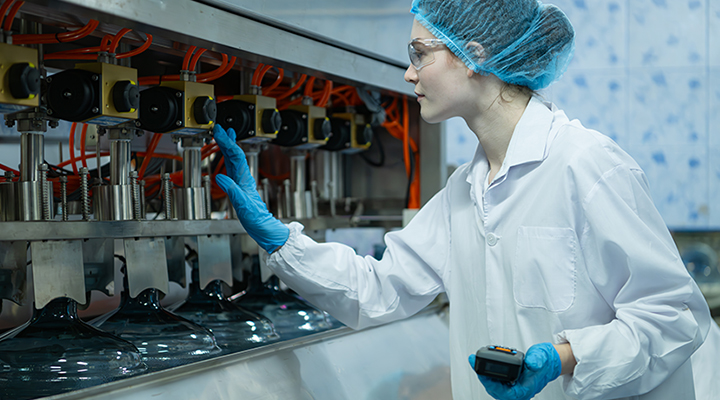 Female employee wearing hygienic PPE while inspecting a production process