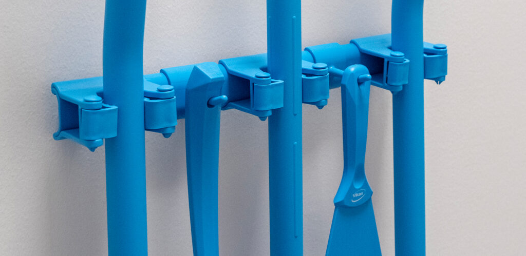 Blue wall-mounted tool holder system with cleaning tools for hygienic workplace organization