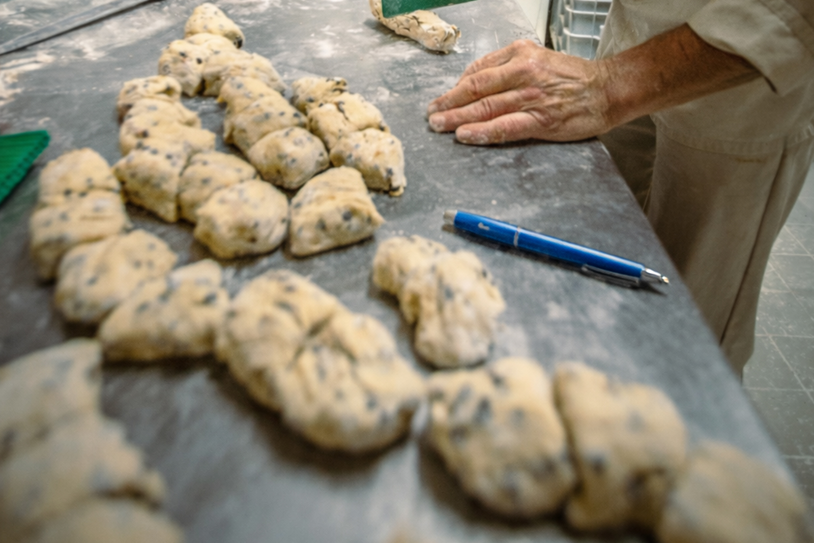 A blue ballpoint pen lying next to seeded dough pieces on a workbench