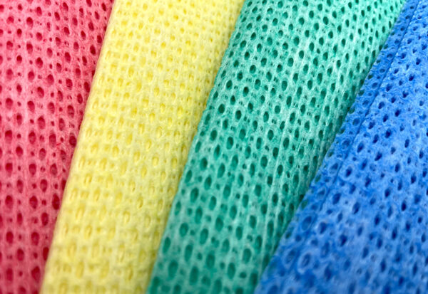 A close-up of four colourful industrial cleaning cloths with an open, textured surface.