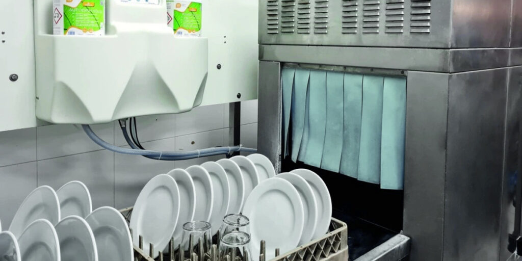 An industrial dishwasher with racks full of tableware