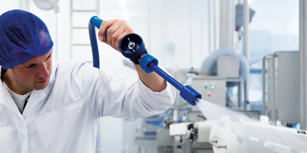 An employee using a foam lance in a production environment
