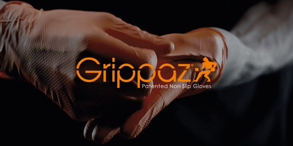 Image of two hands wearing orange Grippaz gloves with logo on a dark background