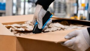 Employee opening a cardboard box with a Martor safety knife in a warehouse environment