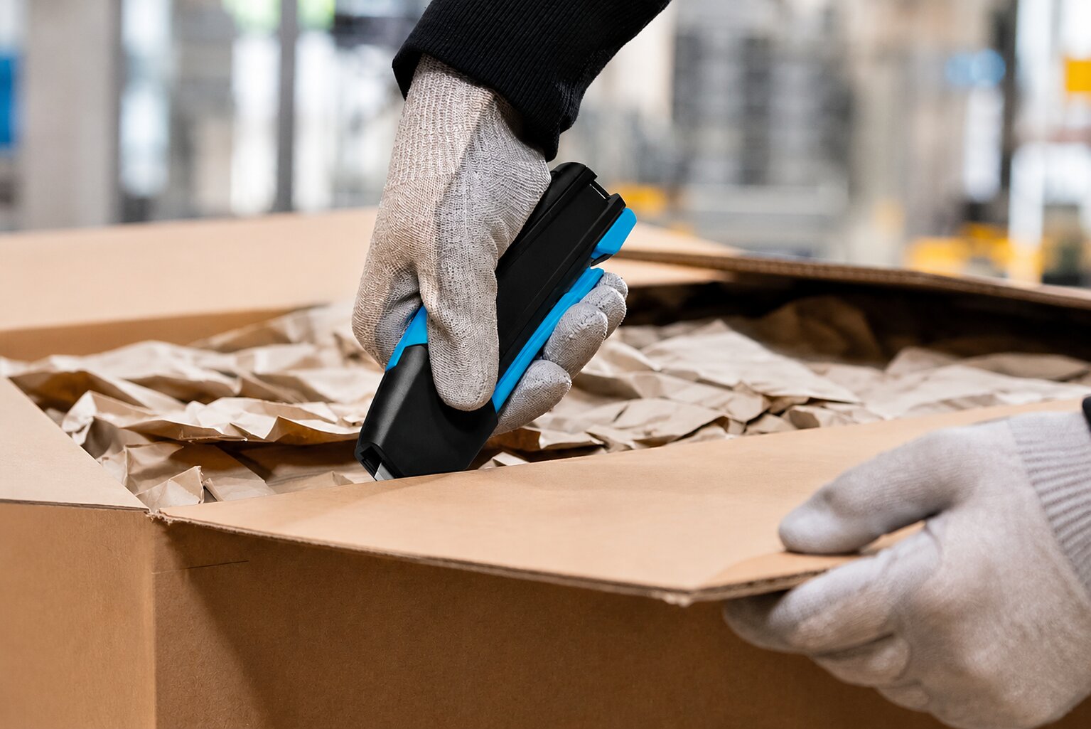 Employee opening a cardboard box with a Martor safety knife in a warehouse environment