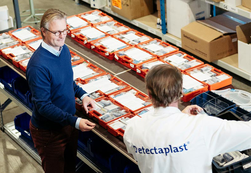 Employees assembling first aid kits at a workbench in the warehouse.