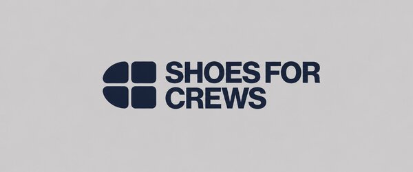 Shoes For Crews logo with a dark blue symbol and dark blue lettering on a light grey background.